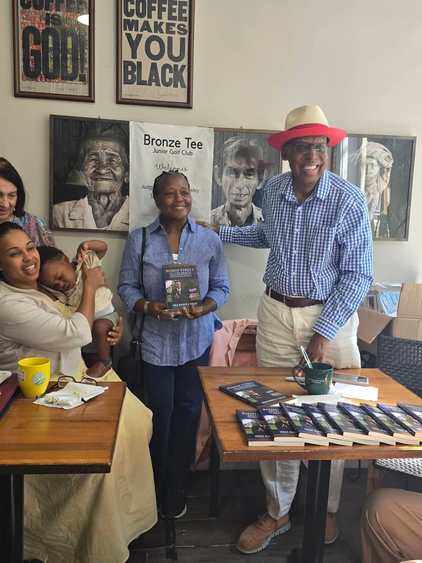 The author with a guest holding a copy of the book and another guest with a baby at the signing