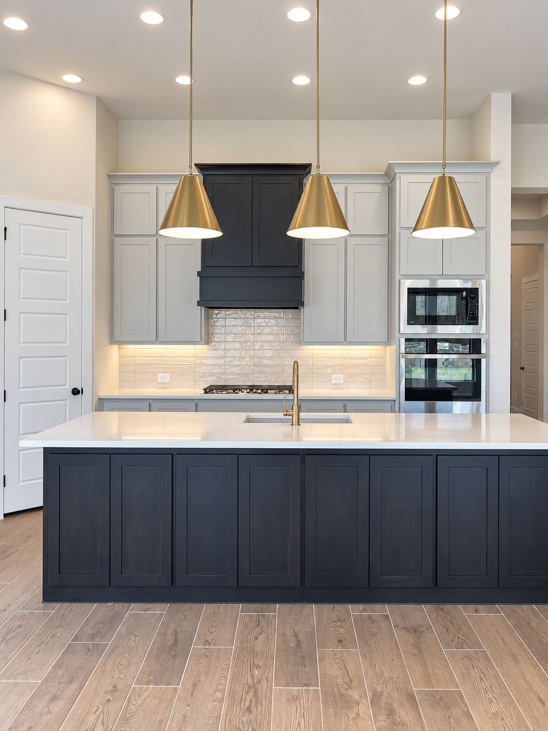 Kitchen with a large island, three pendant lights, two-tone cabinetry and built-in appliances, photographed during my Perry Homes visit at The Parks at Wilson Creek in Celina.