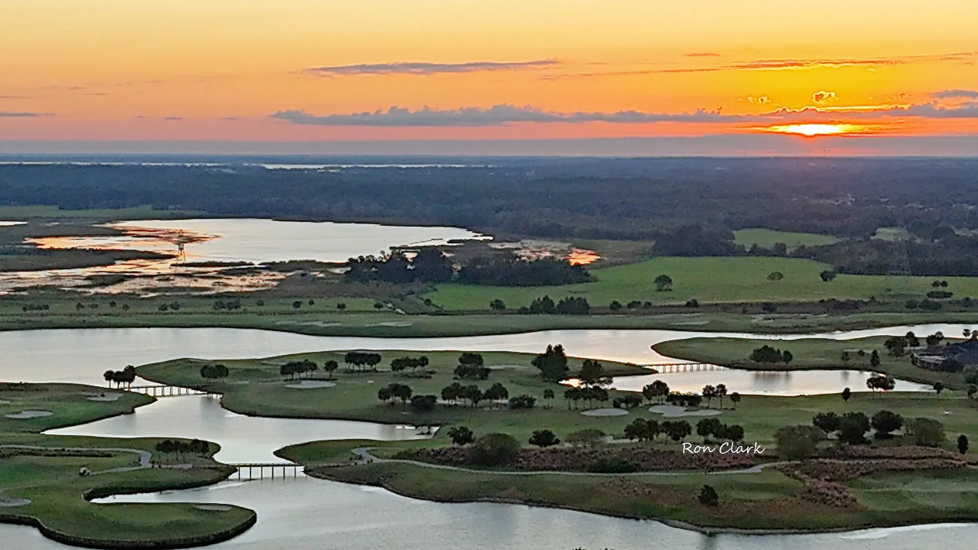 An aerial view of a Florida golf course winding through lakes at sunset