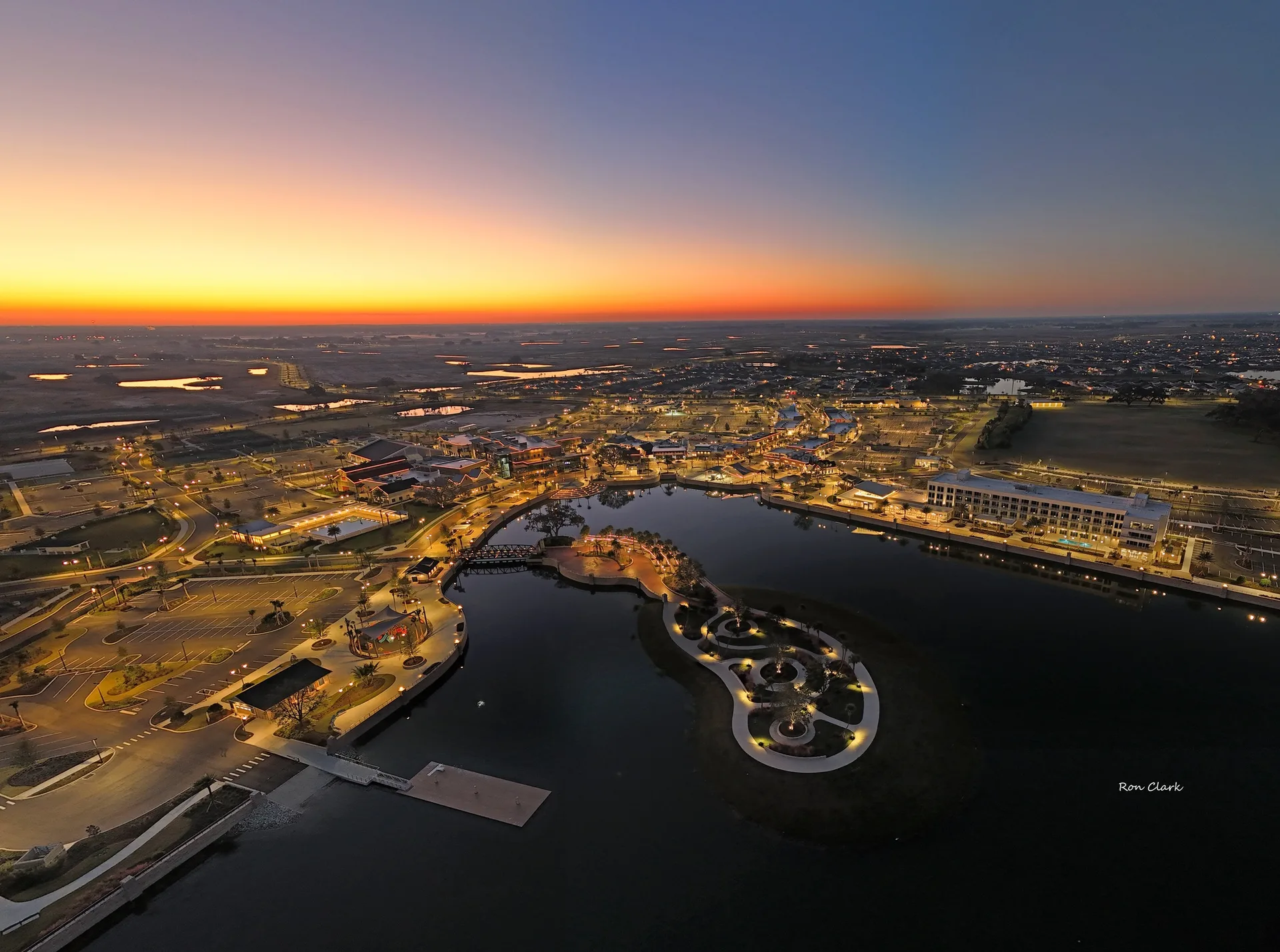 An aerial twilight view of a suburban Florida town and waterfront park illuminated by streetlights