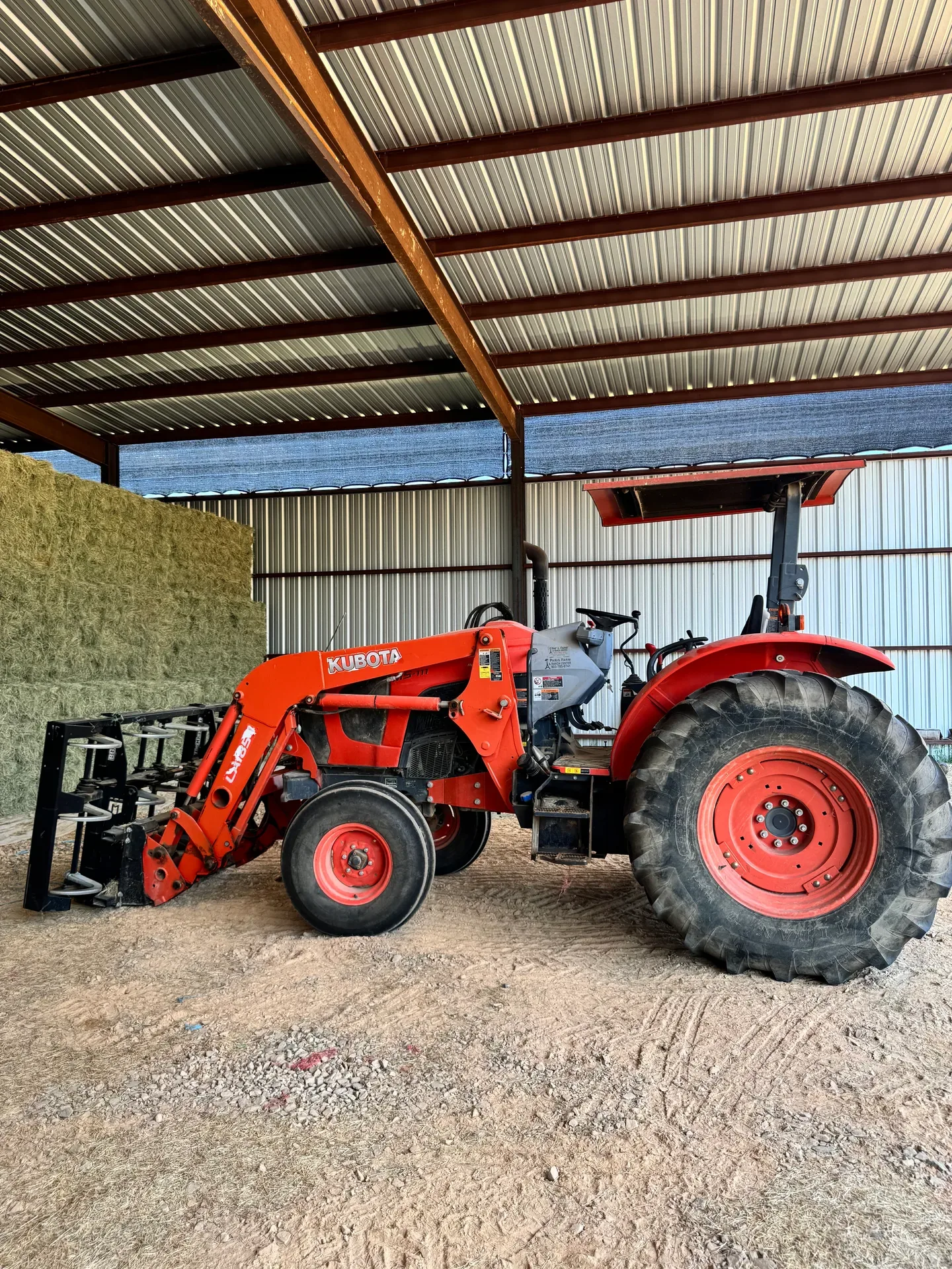 Kubota tractor in a barn with hay bales