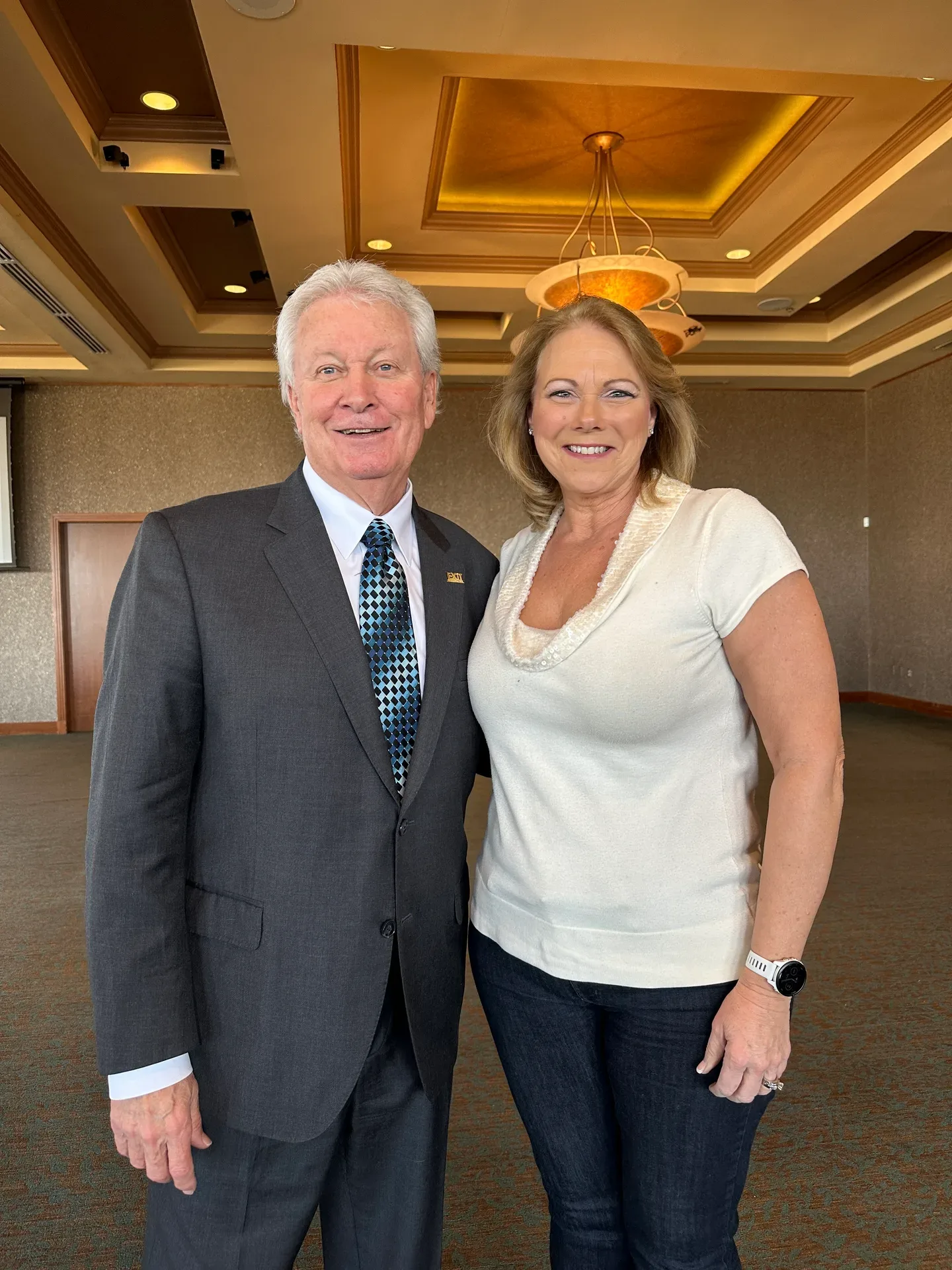 Bev Prock standing next to an older man in a suit inside an upscale event room