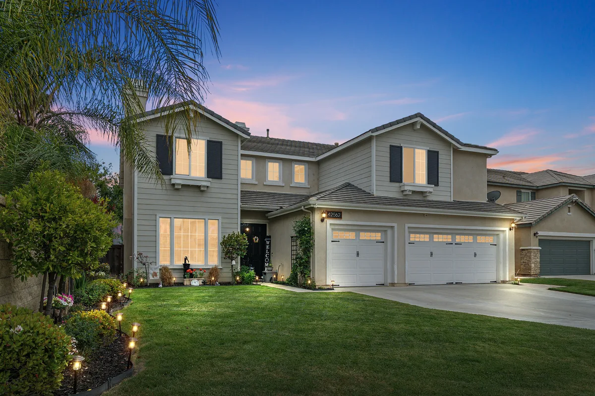Two-story suburban home with illuminated windows and landscape lighting at dusk in Murrieta