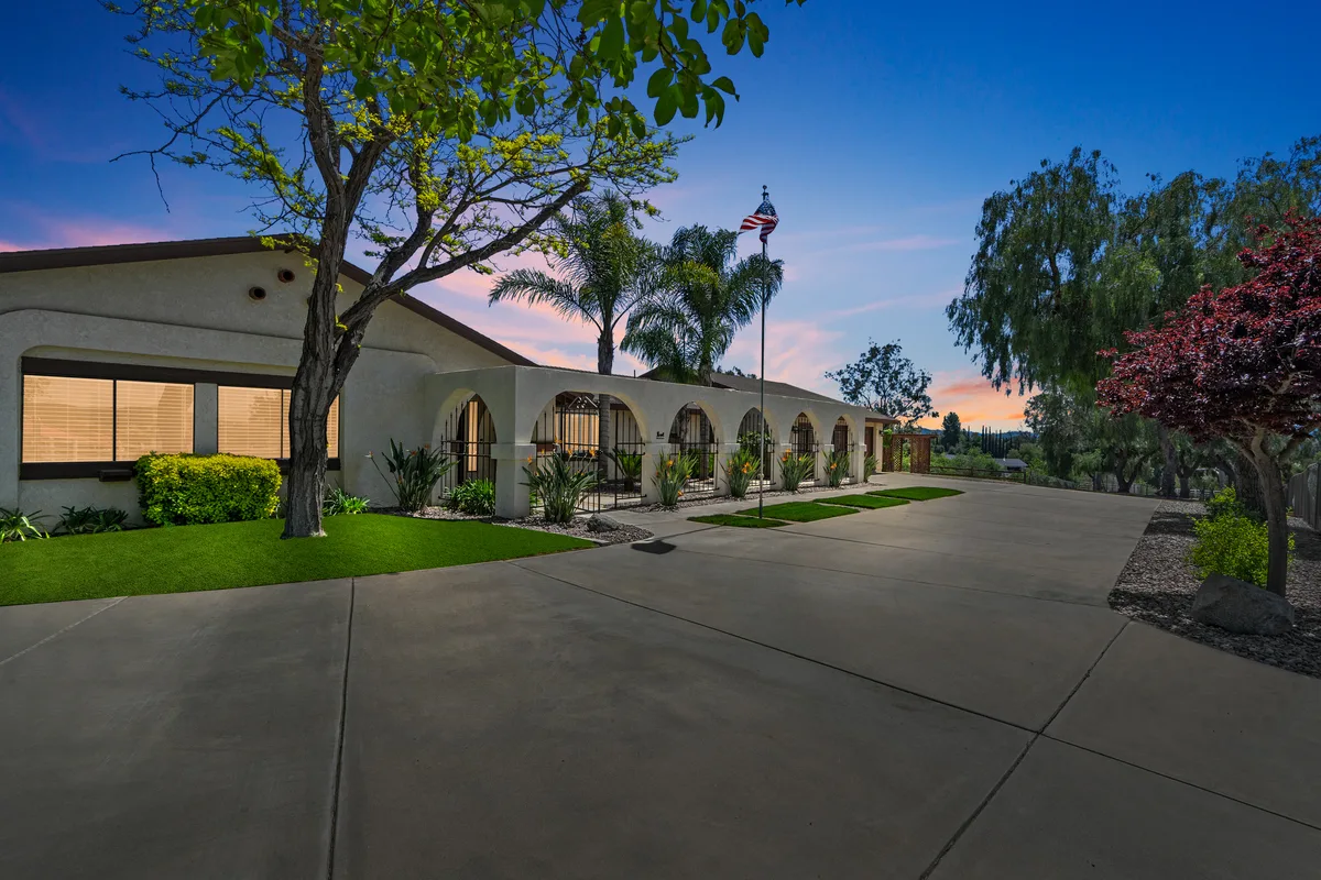 Single-story suburban house with a long arched walkway and a paved driveway at dusk in Murrieta