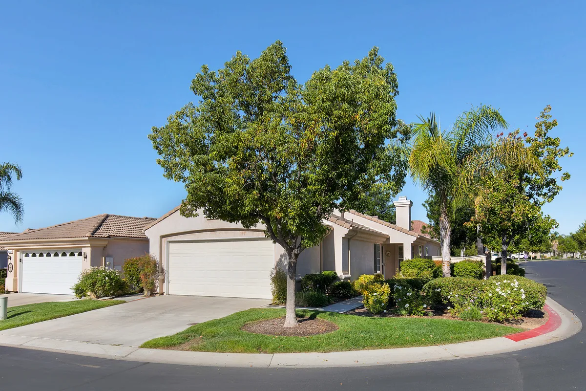 Single-story suburban house with two-car garage and landscaped front yard under a clear blue sky in The Colony