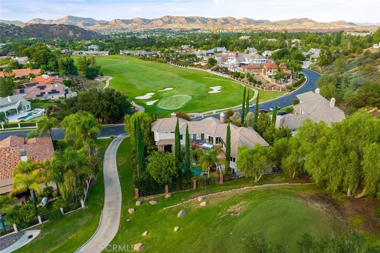 Aerial view of a residential neighborhood adjacent to a golf course and rolling hills in Bear Creek