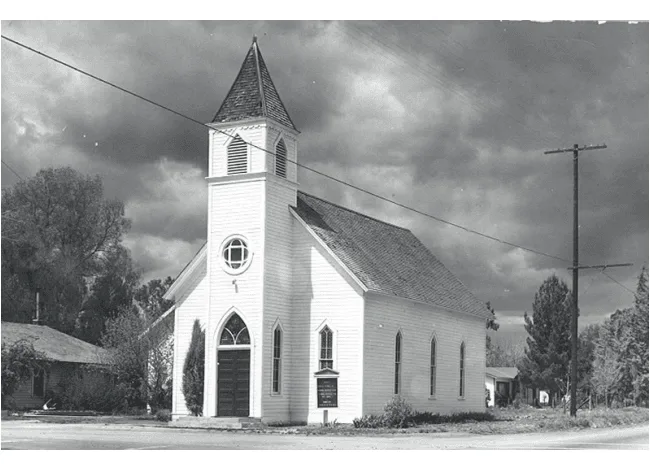 Black and white photograph of a historic wooden church building under a cloudy sky