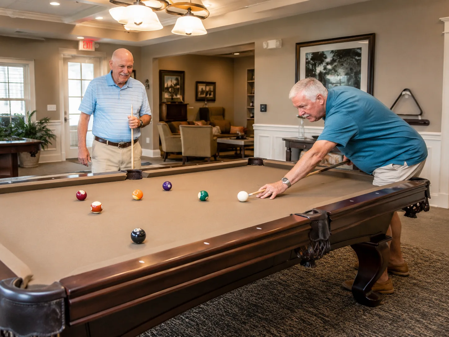 Two older men playing billiards in a warm recreation room at The Colony clubhouse