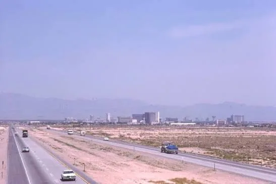 Multi-lane highway leading toward a desert city skyline under a clear blue sky