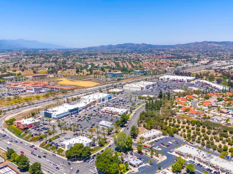 Aerial wide-angle shot of a suburban commercial area with shopping centers and surrounding residential neighborhoods