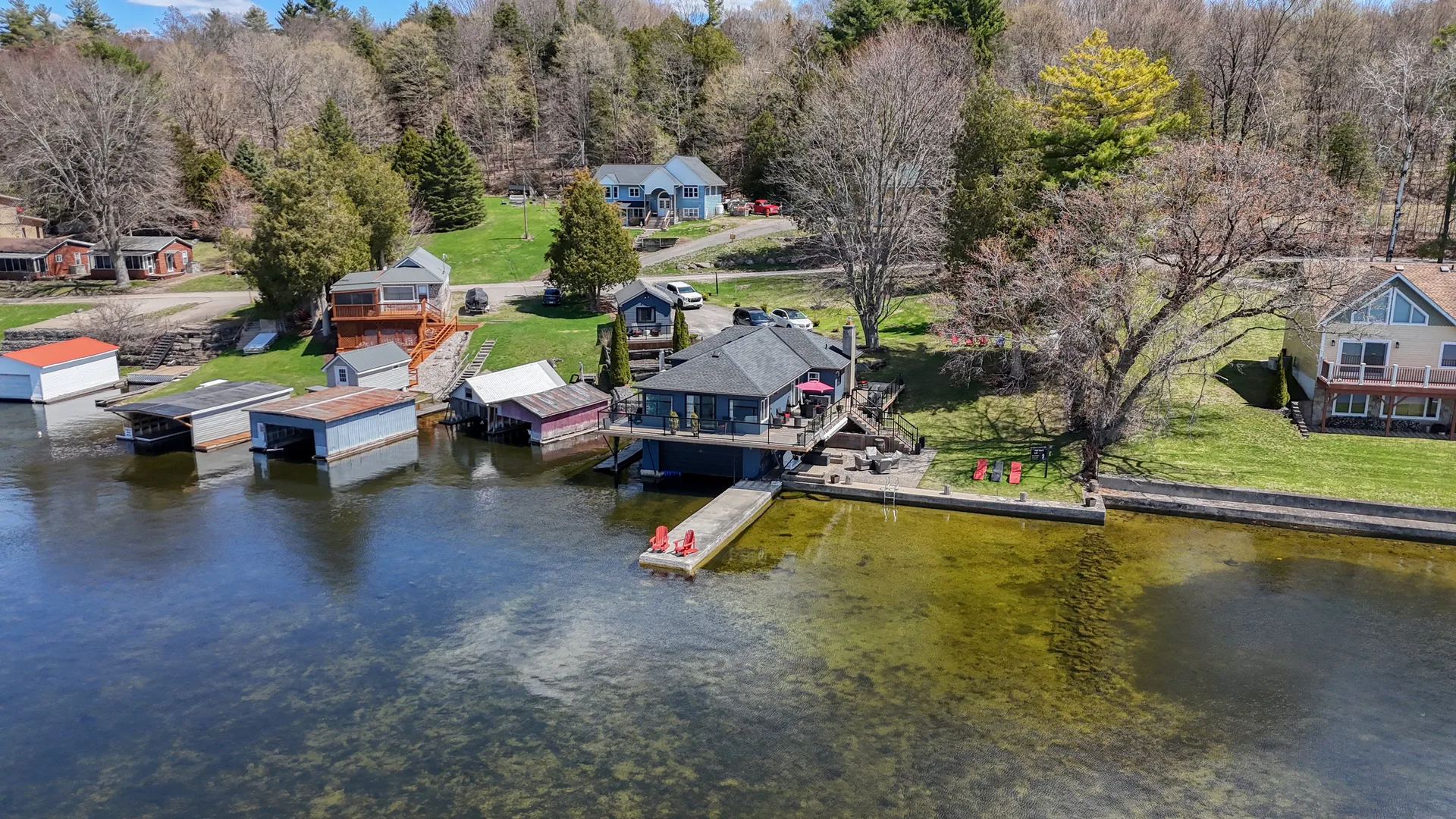 Aerial drone view of several houses along a lakeshore with boat houses and private docks in Kingston Ontario