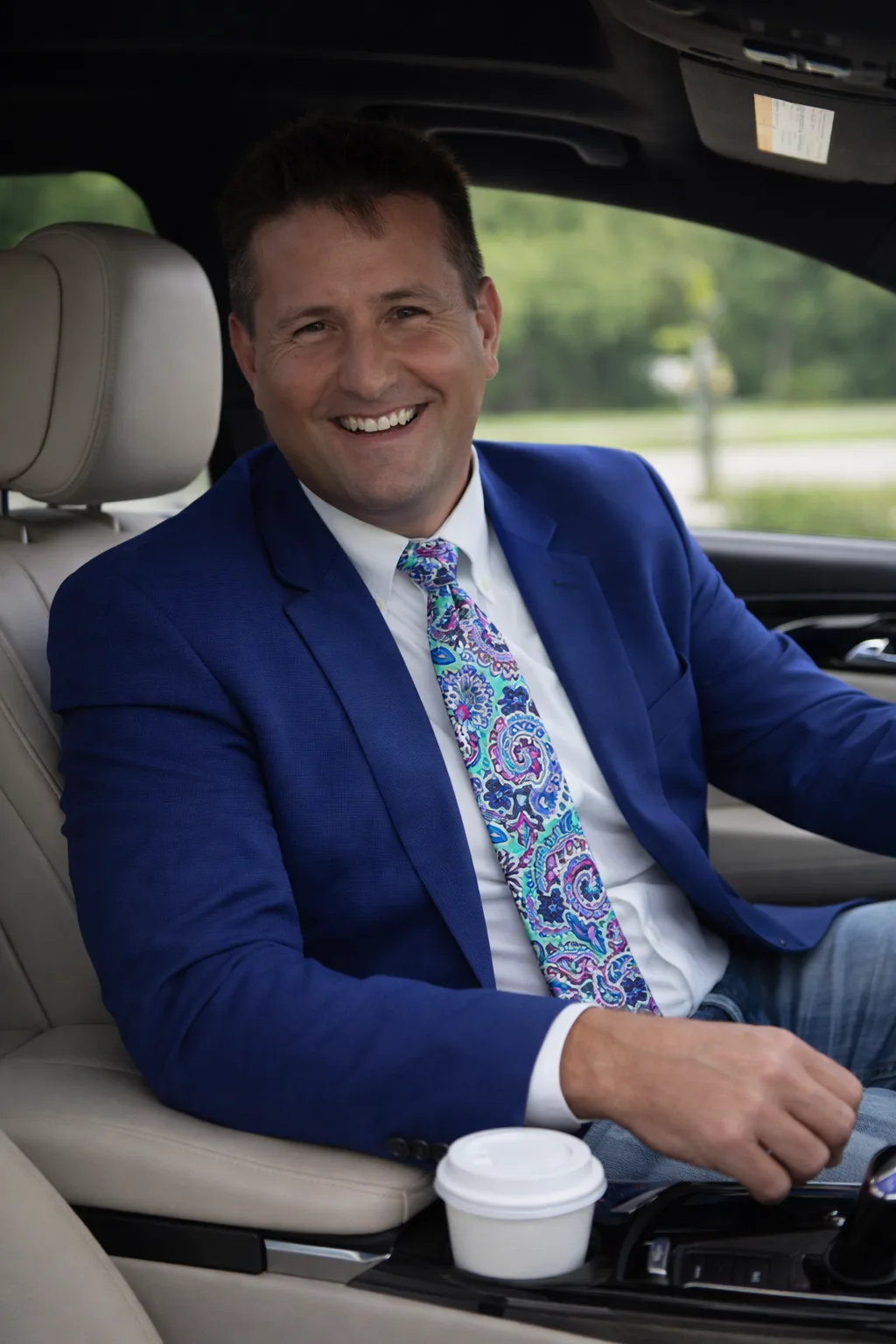 Rob Dietrich in a blue blazer in the driver's seat of a car