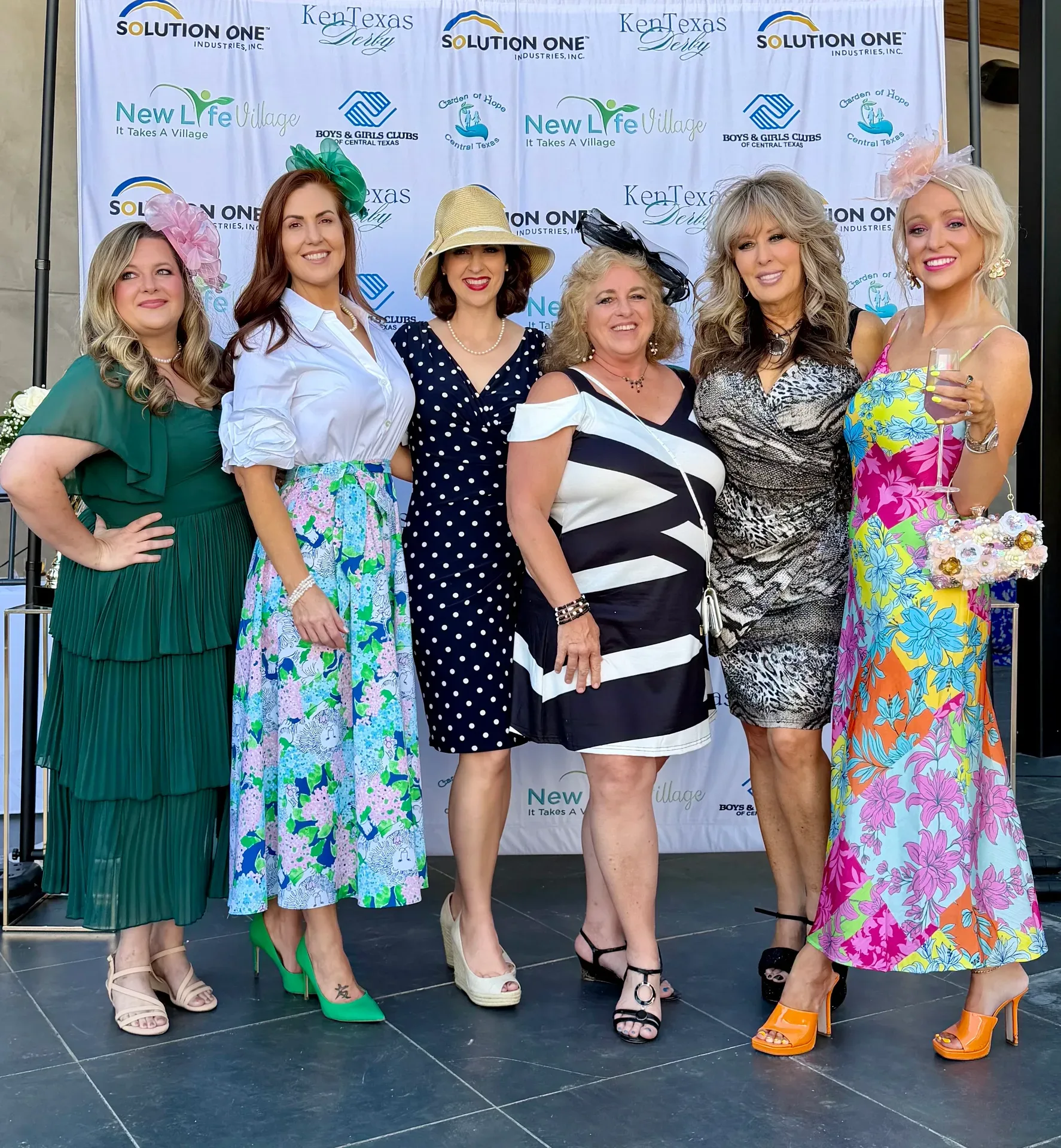 Lisa Copeland with six women in formal attire and hats posing at a charity derby event