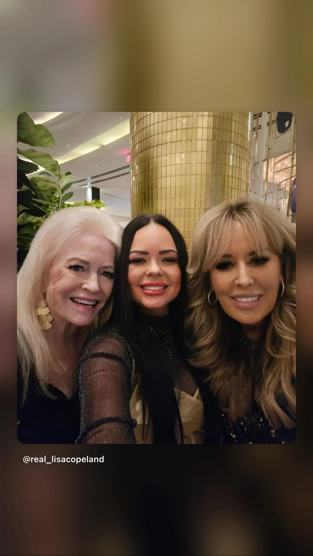 Lisa Copeland taking a selfie with two women at an evening event with a gold-tiled pillar