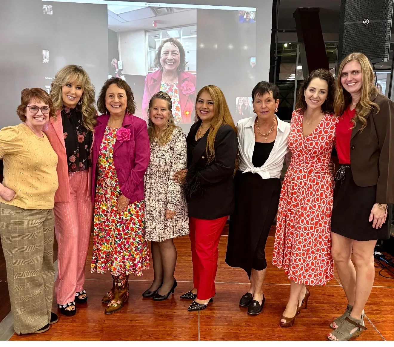 Lisa Copeland with seven women at a hybrid event in front of a large screen