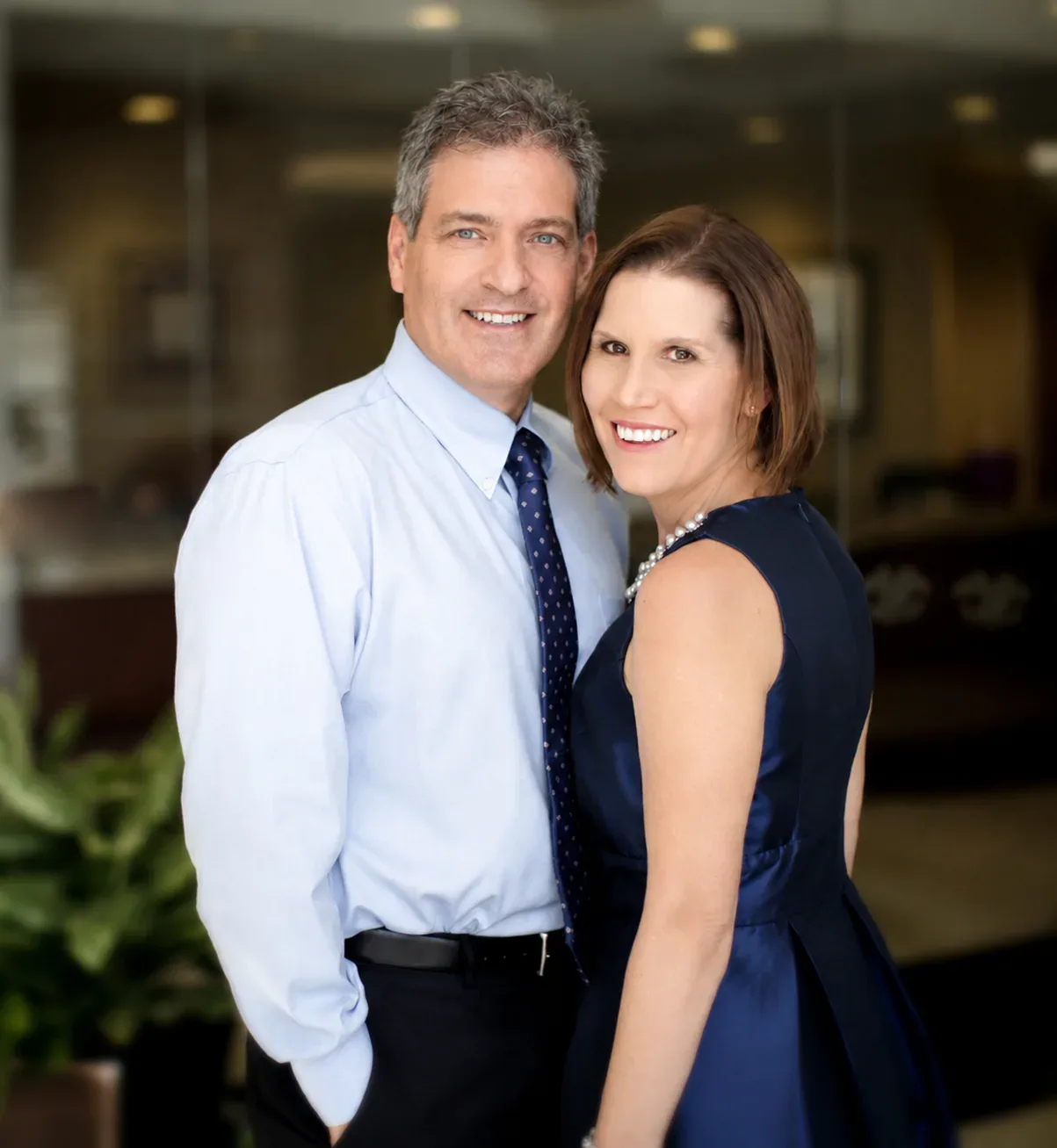 Phil Alu and Denise Alu of Alu Realty Group standing together in their office