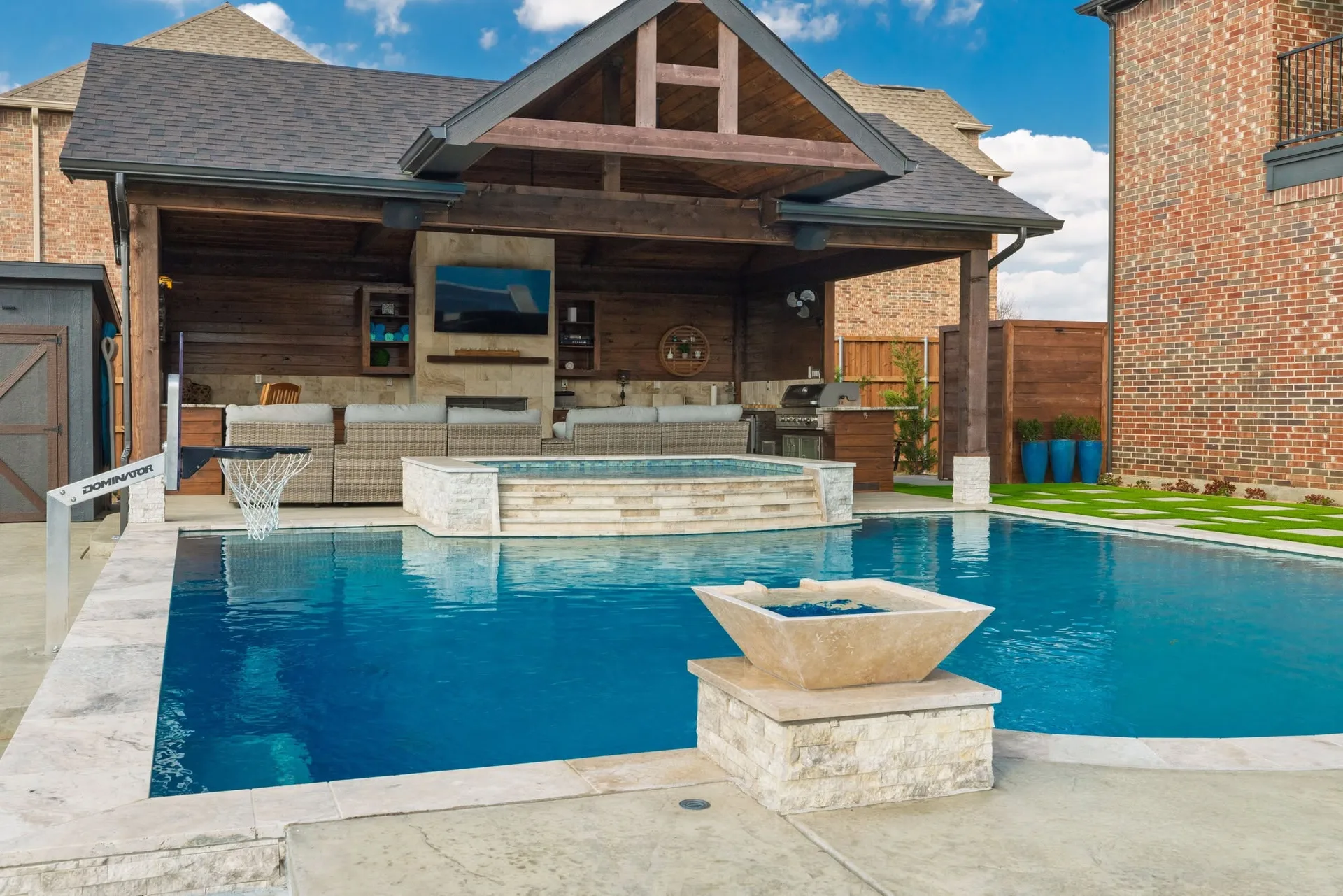 A finished backyard with a swimming pool, built-in spa, and covered patio seating