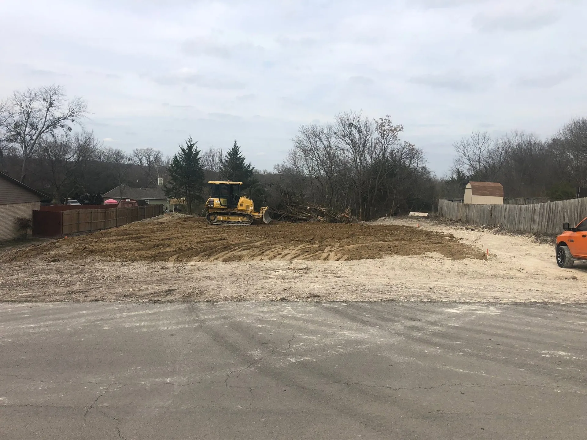 A bulldozer clearing and leveling a vacant residential lot before construction begins