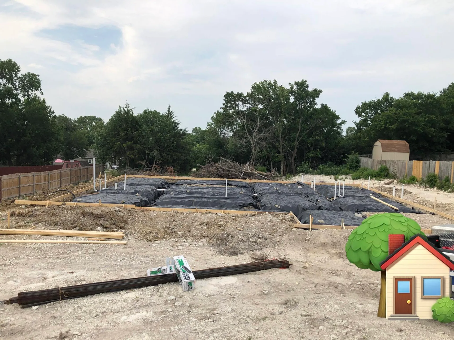 A house foundation poured over black plastic sheeting on a new construction site