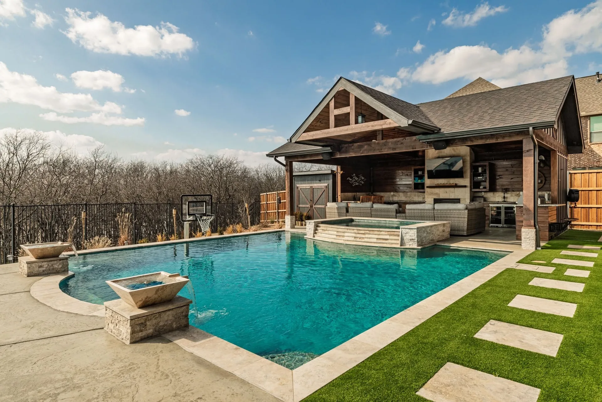 A luxury backyard with a swimming pool, integrated hot tub, and covered patio seating
