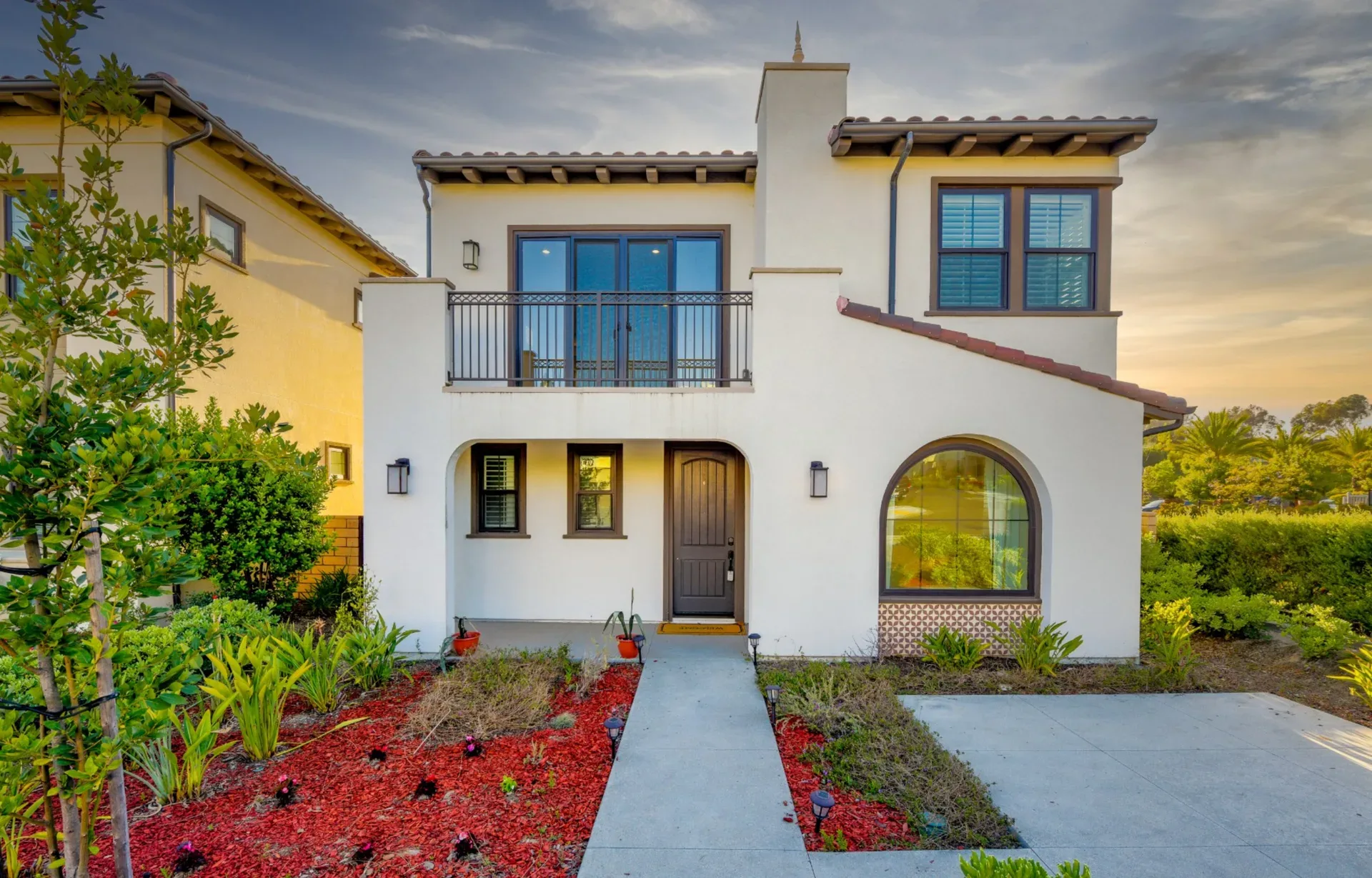 A modern two-story Spanish-style home exterior at sunset