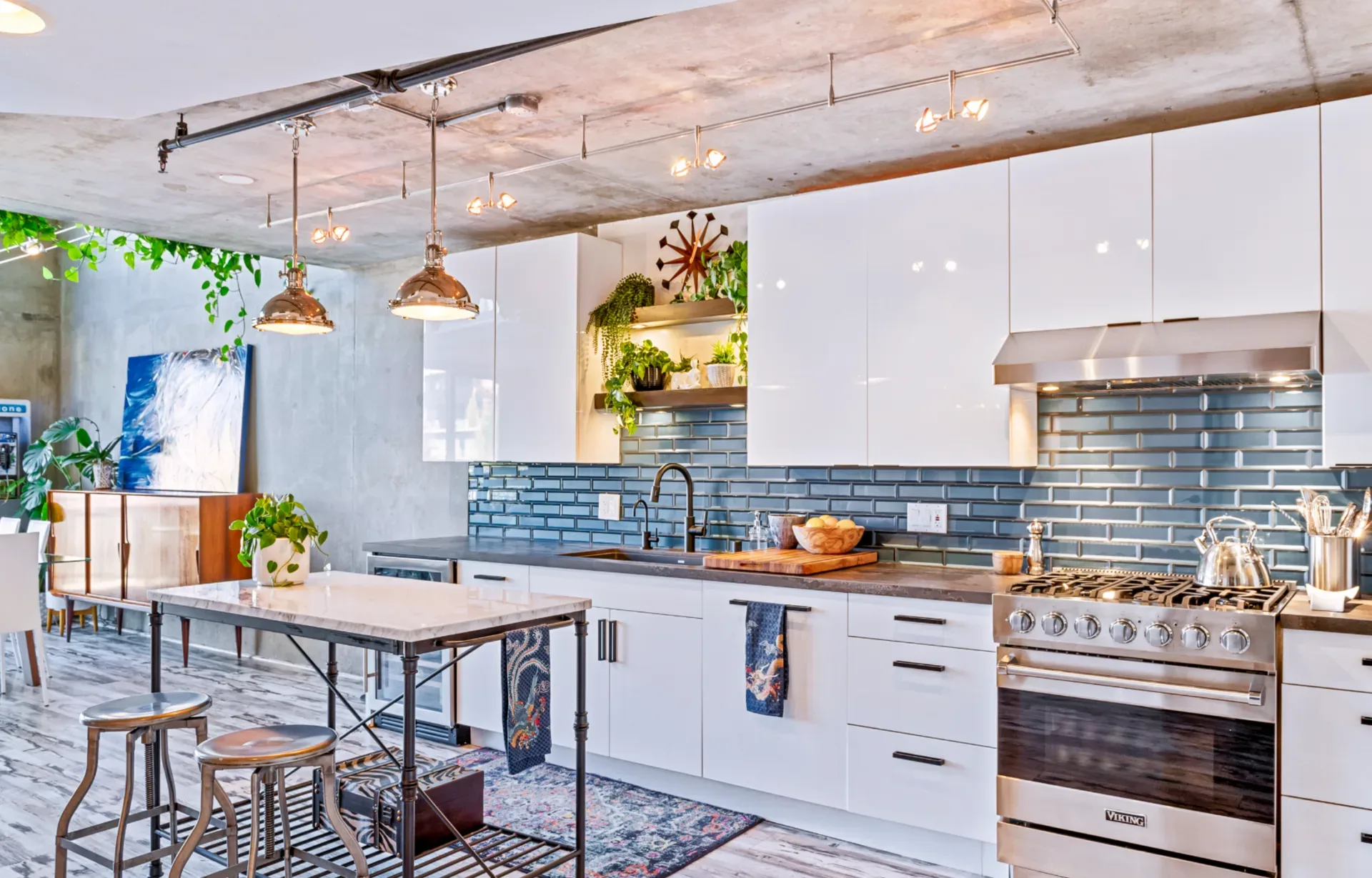 Modern kitchen with white cabinets, blue subway tiles, and a concrete ceiling