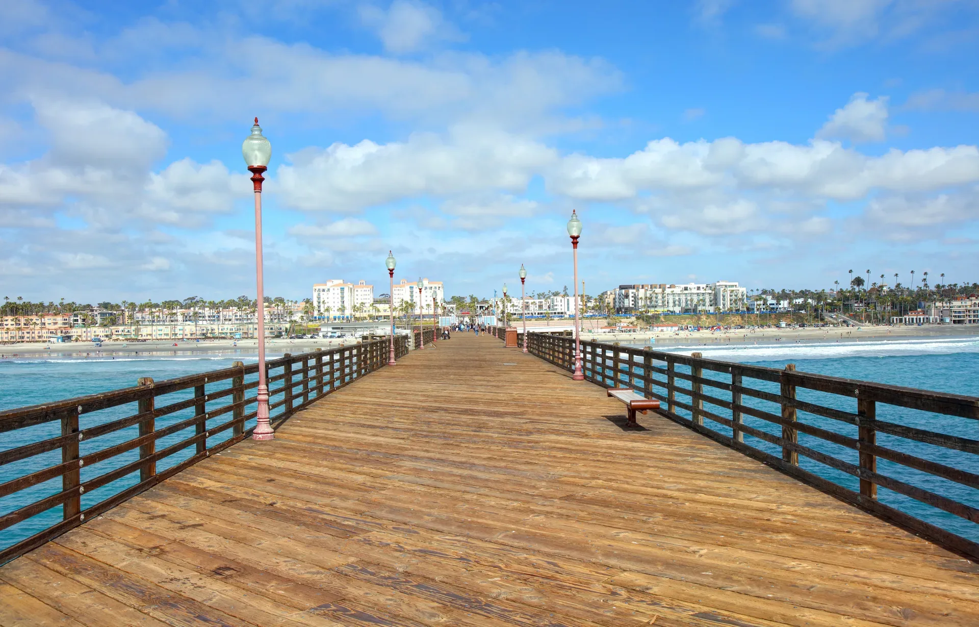 The wooden Oceanside pier looking toward the coastal city skyline under a blue sky