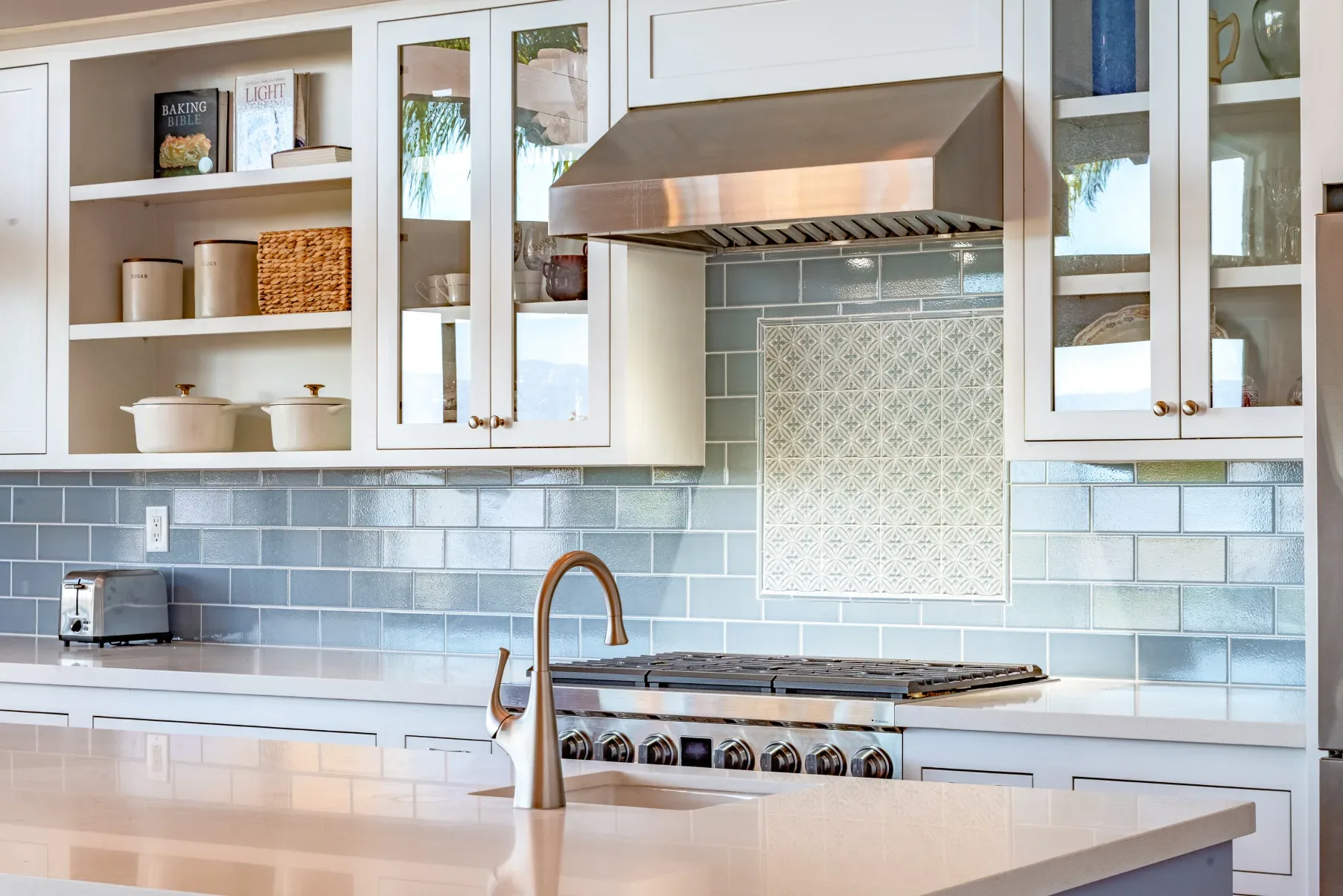 Bright modern kitchen with white cabinets, stainless steel appliances, and a light blue tiled backsplash