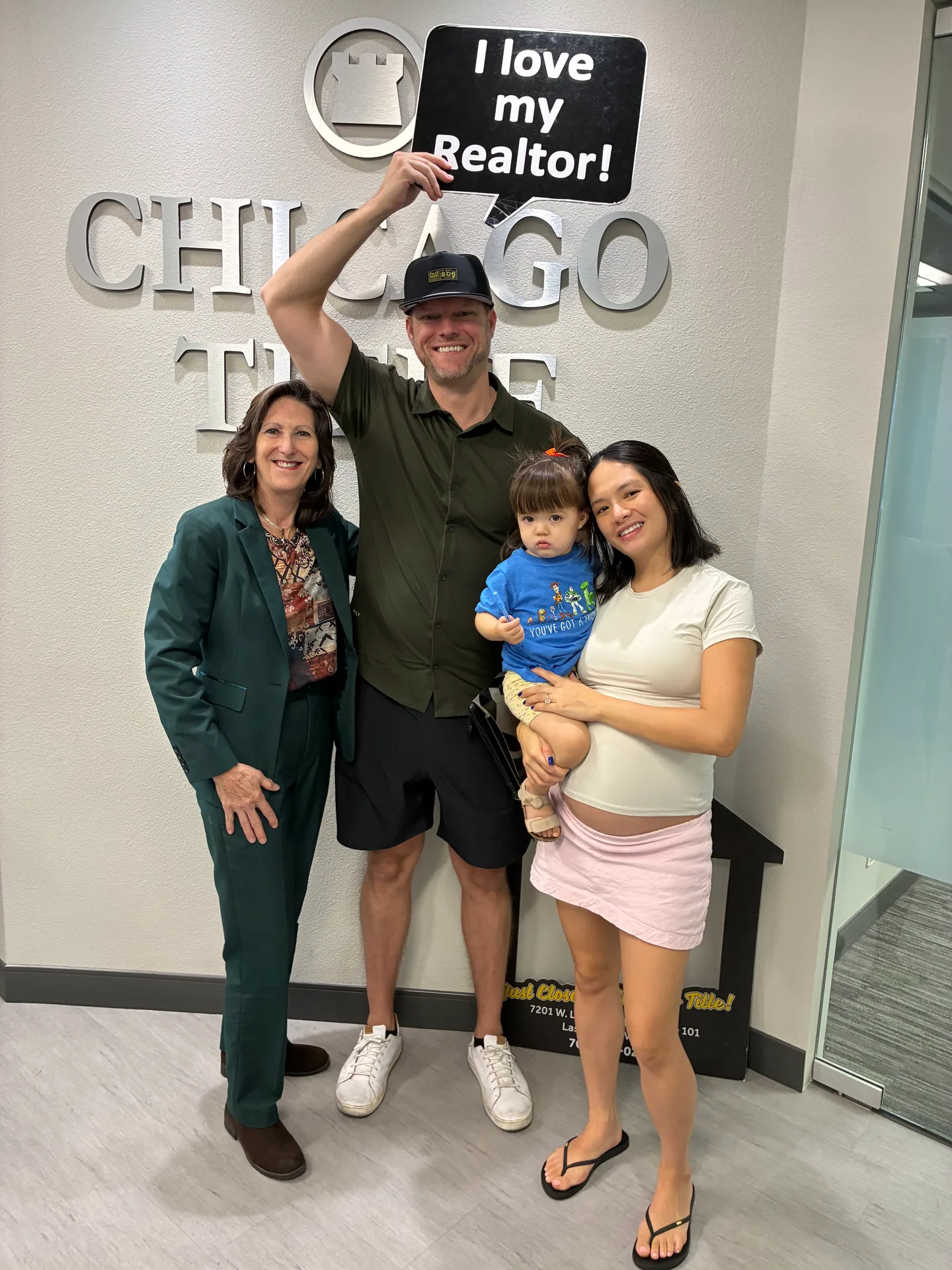 Sandy Margolin celebrating with a happy family holding an I love my Realtor sign