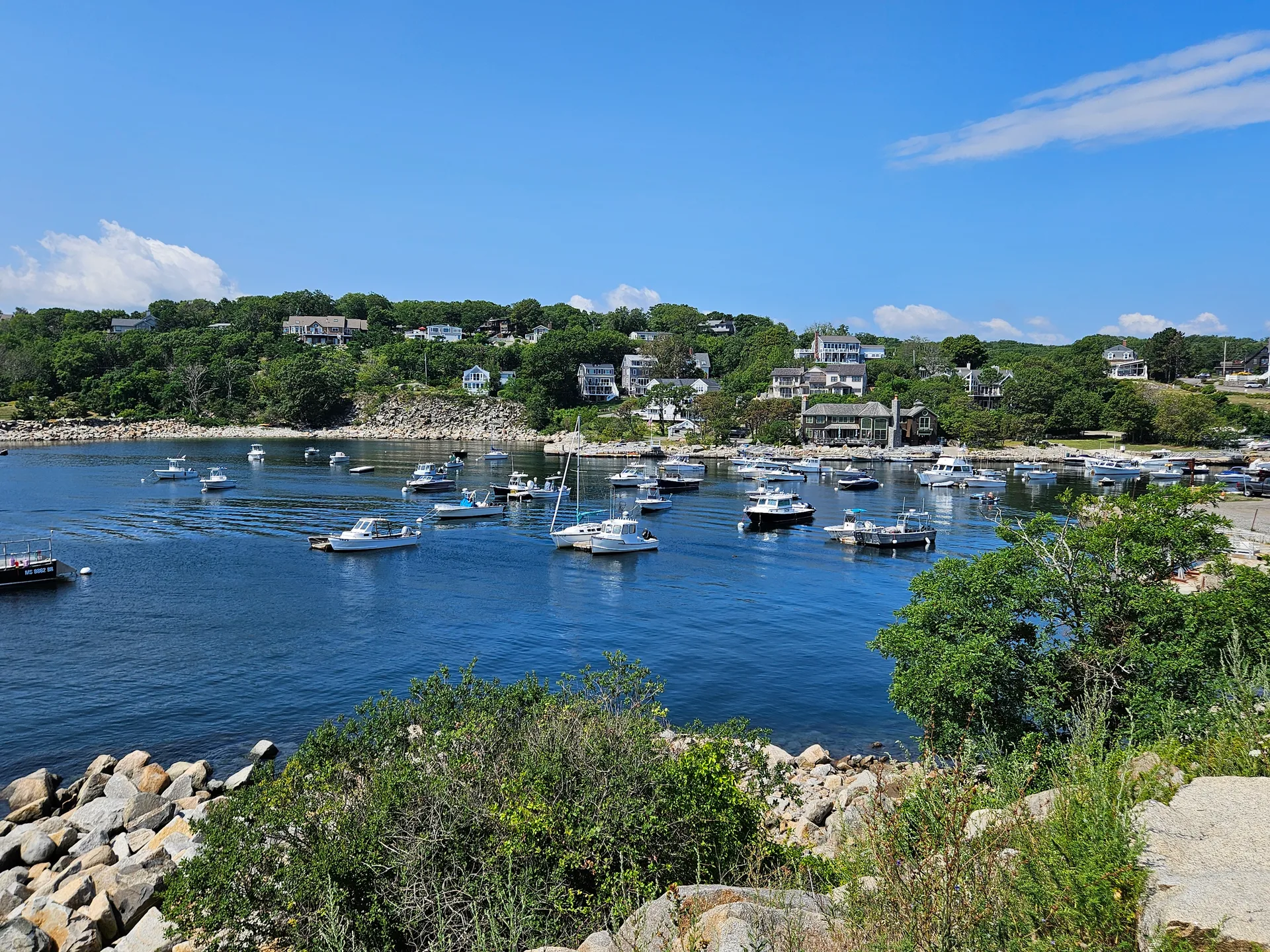 A scenic coastal harbor filled with boats under a bright blue sky