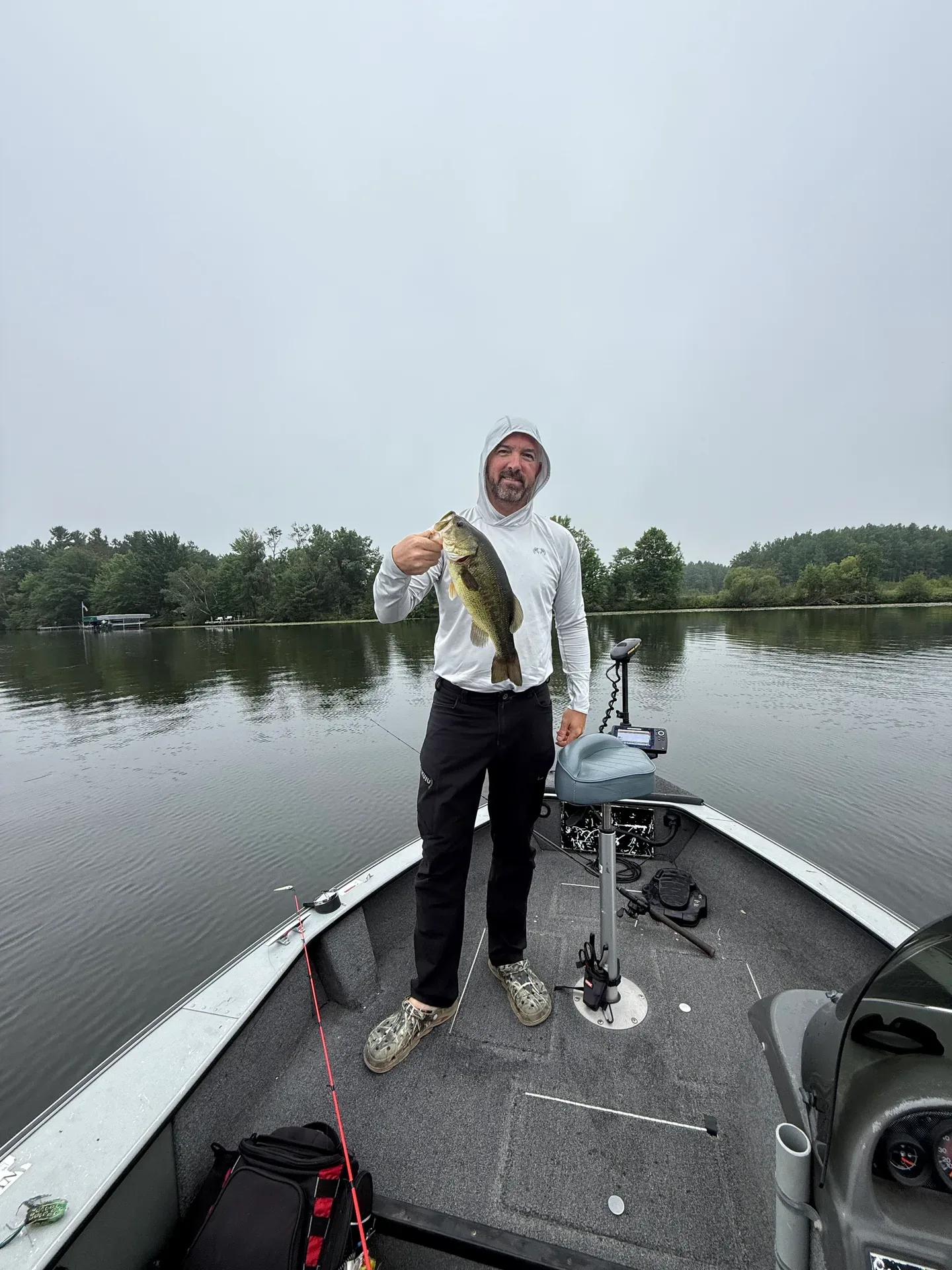 Josh on a calm lake holding a bass he just caught