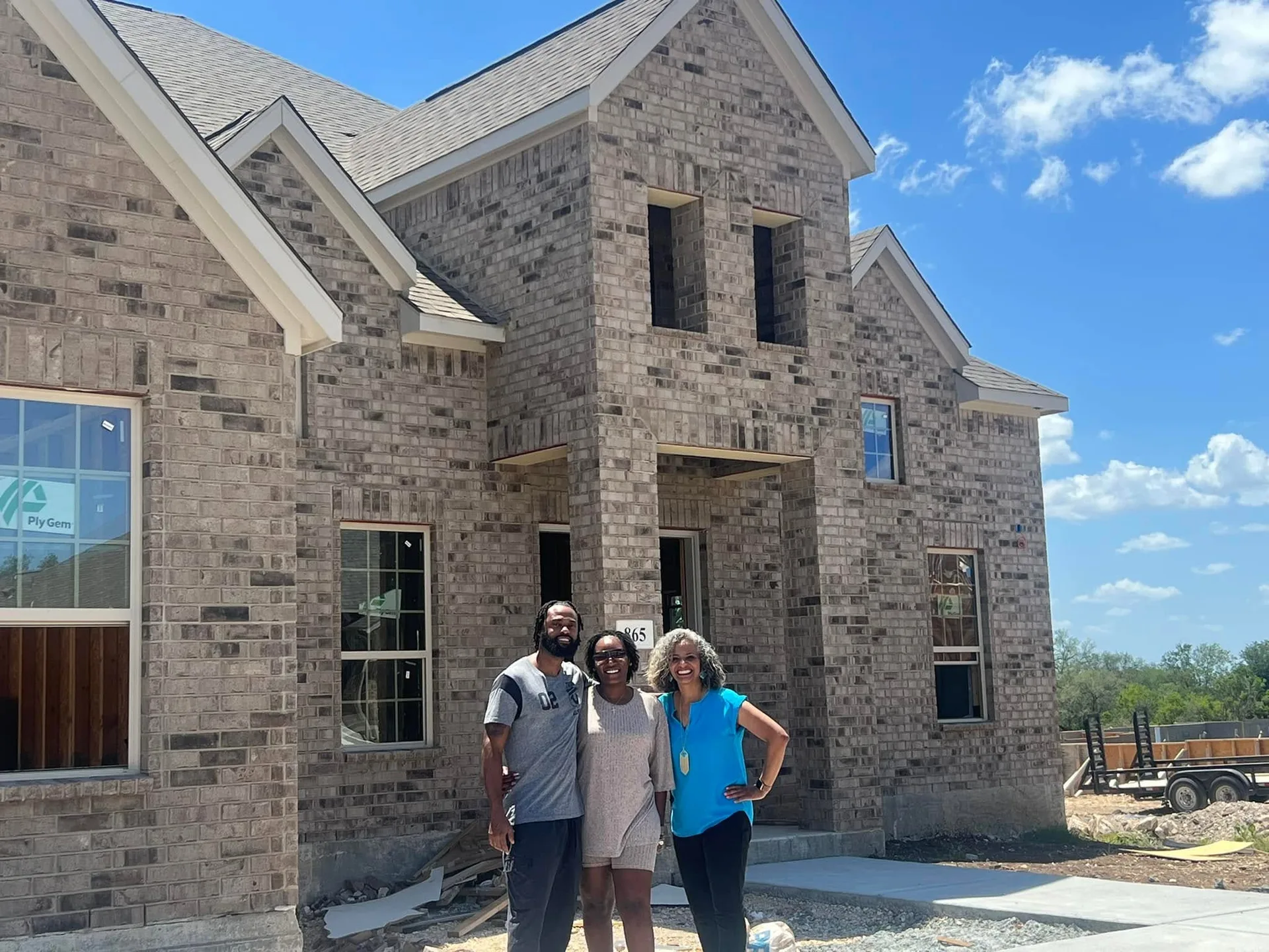 Tami Price with a couple in front of a partially constructed new home