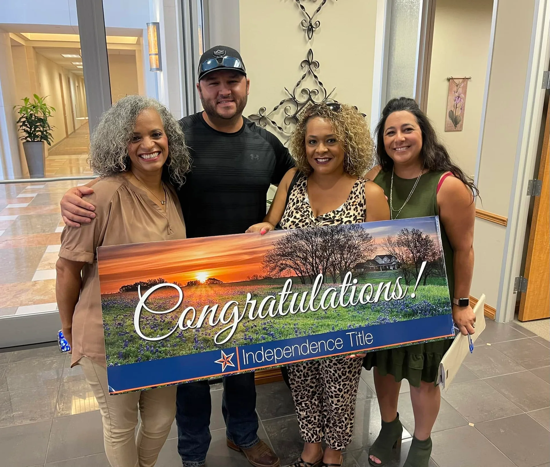 Tami Price with three clients holding a Congratulations sign from Independence Title on closing day