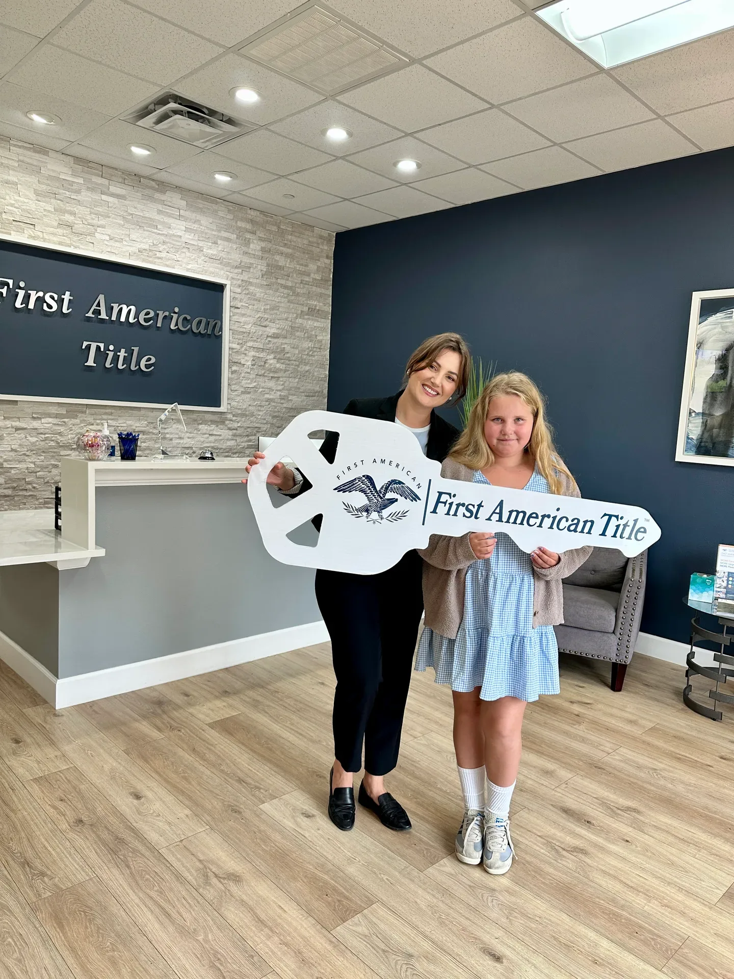 A client holding a large title company commemorative key on closing day