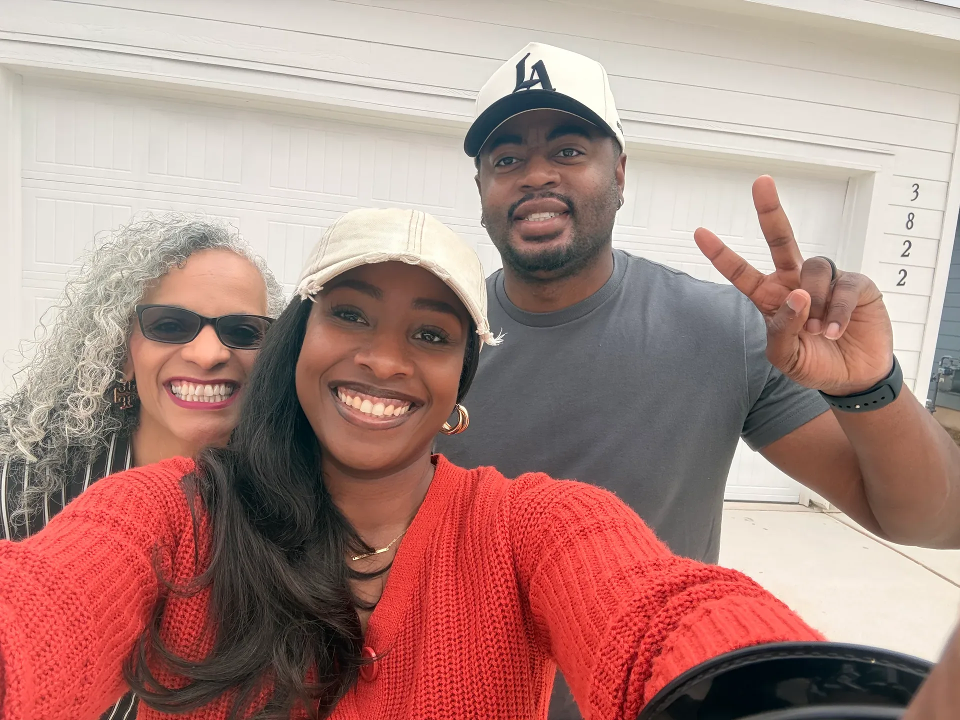 Tami Price taking a smiling selfie with a couple outside their home