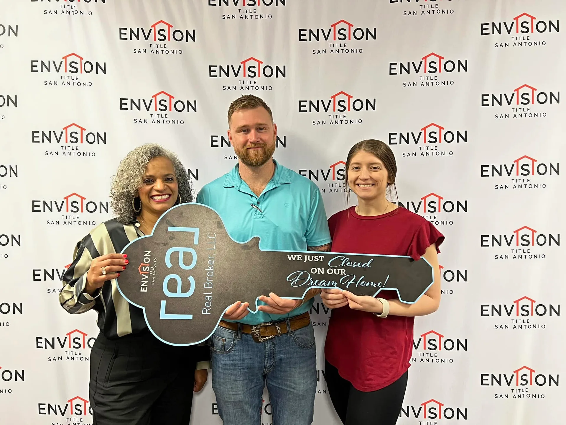 Tami Price with a couple holding a large prop key at a closing celebration