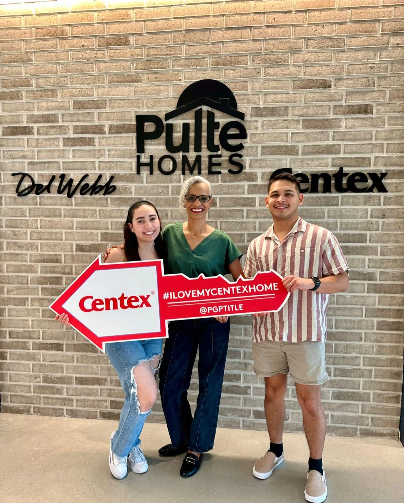 Tami Price with two clients holding a large red key prop in front of a brick wall