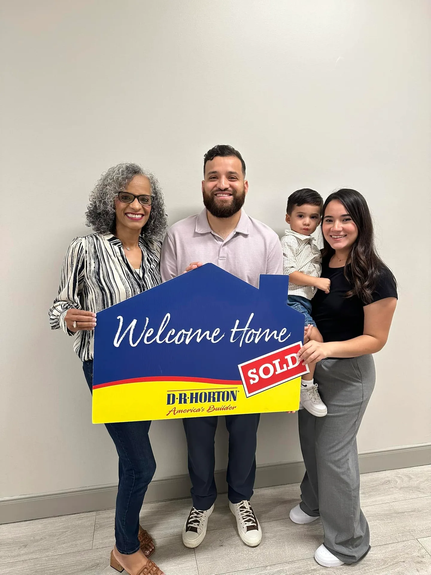 Tami Price with a family holding a Welcome Home sold sign on closing day