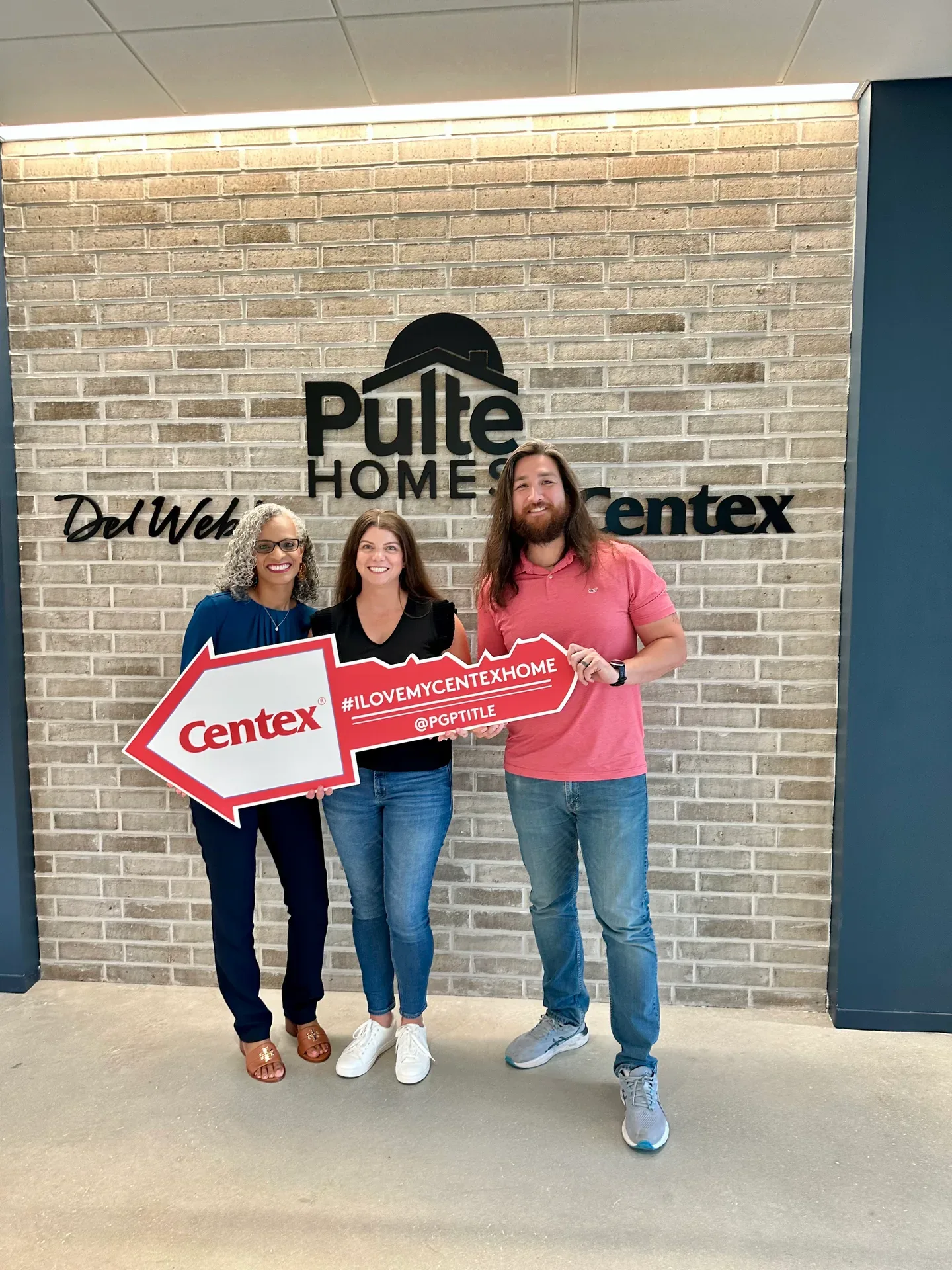 Tami Price with a couple holding a large Centex key prop on closing day