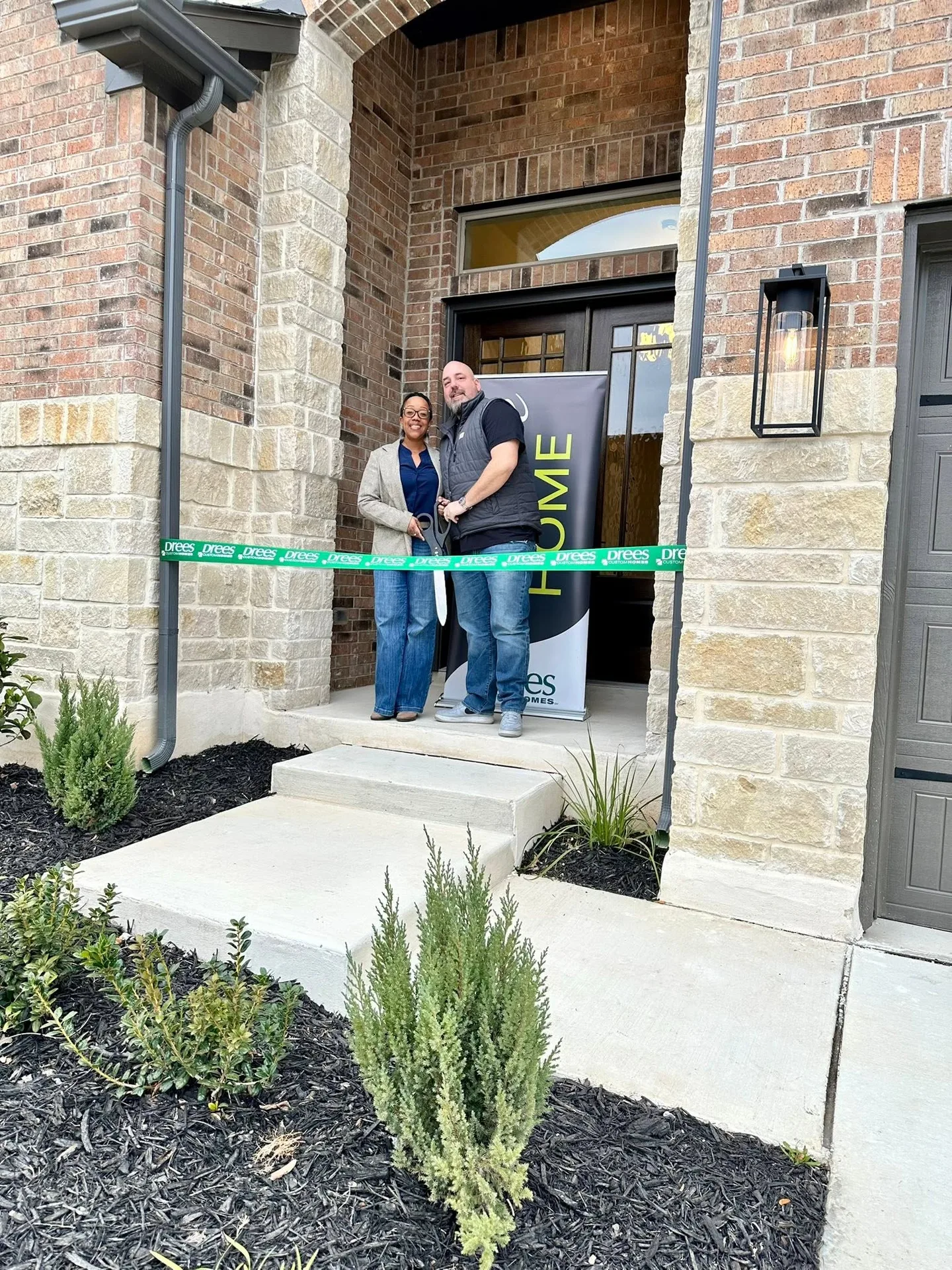 Tami Price cutting the ribbon at the front door of a new home