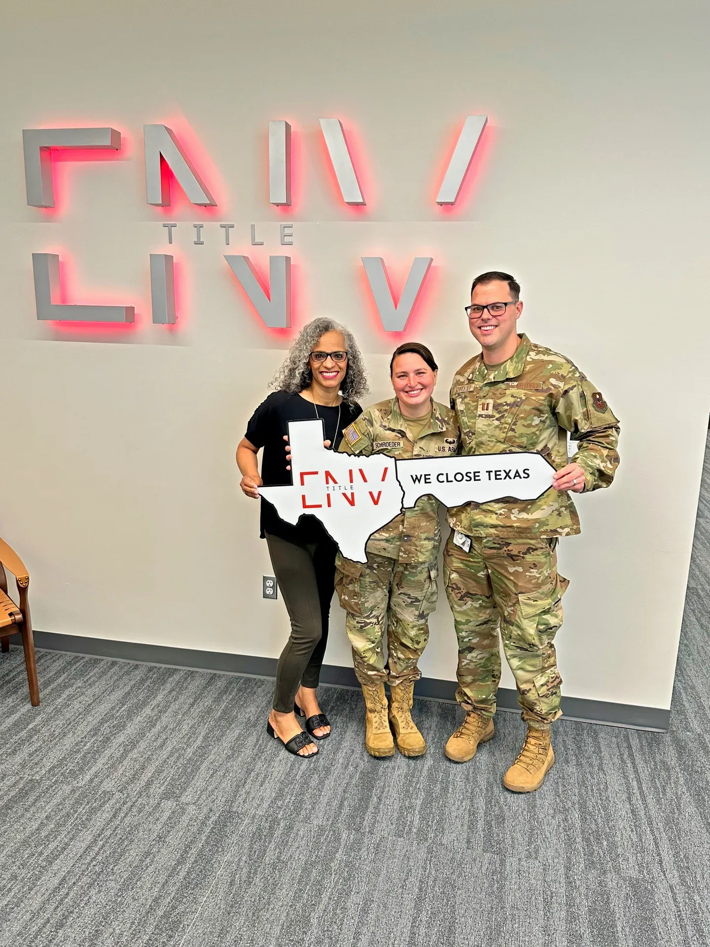 Tami Price with a military couple holding a Texas-shaped WE CLOSE TEXAS sign on closing day