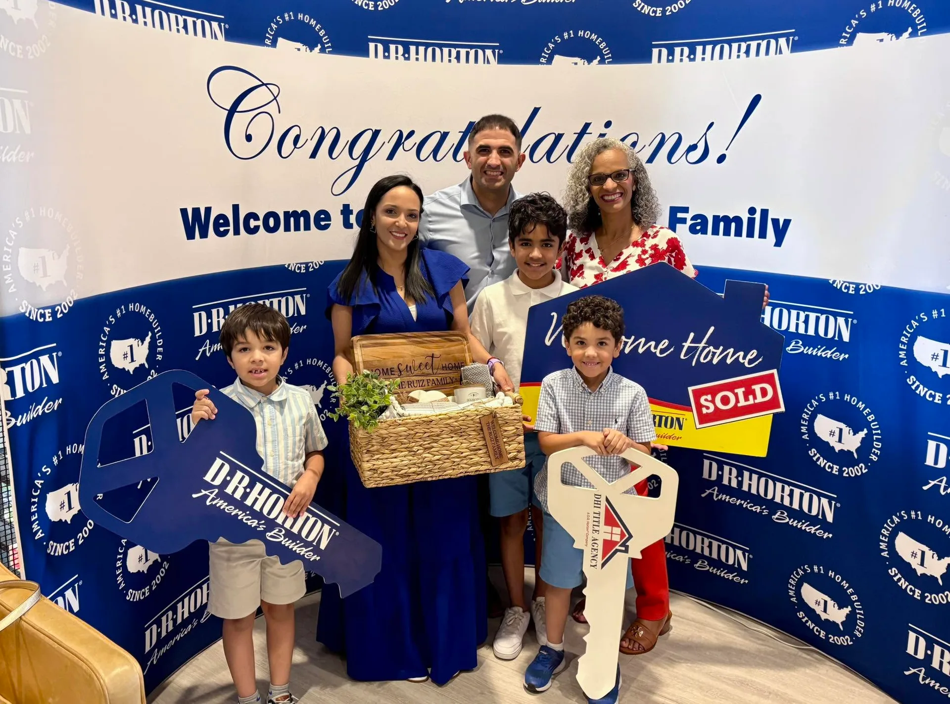 Tami Price with a client family in front of a D.R. Horton backdrop at a closing celebration