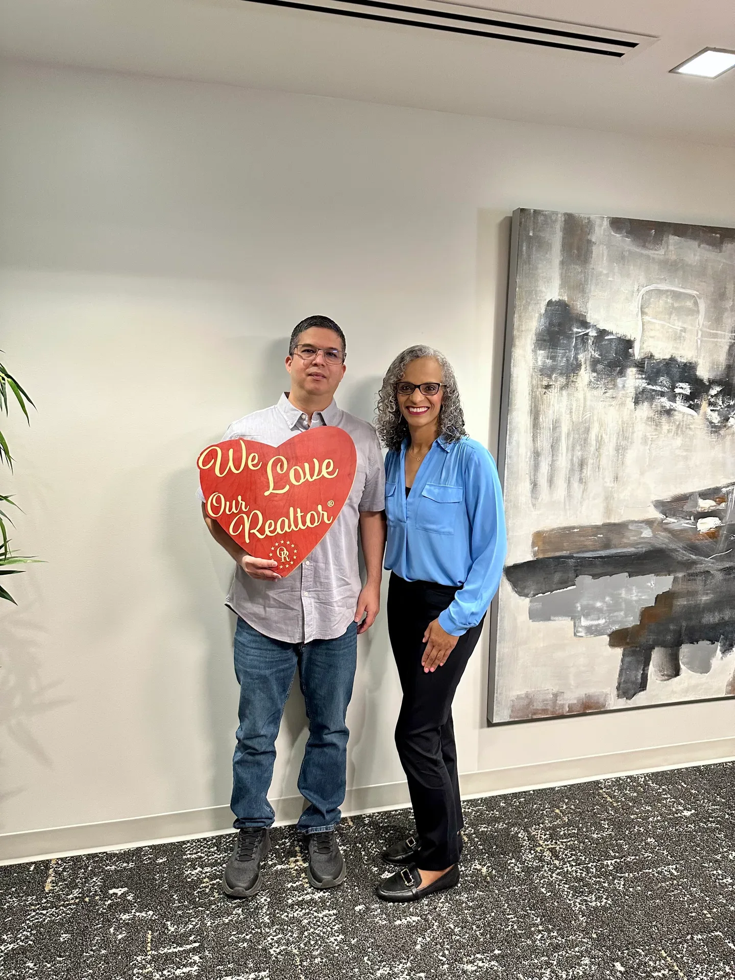 Tami Price with a client holding a heart-shaped We Love Our Realtor sign