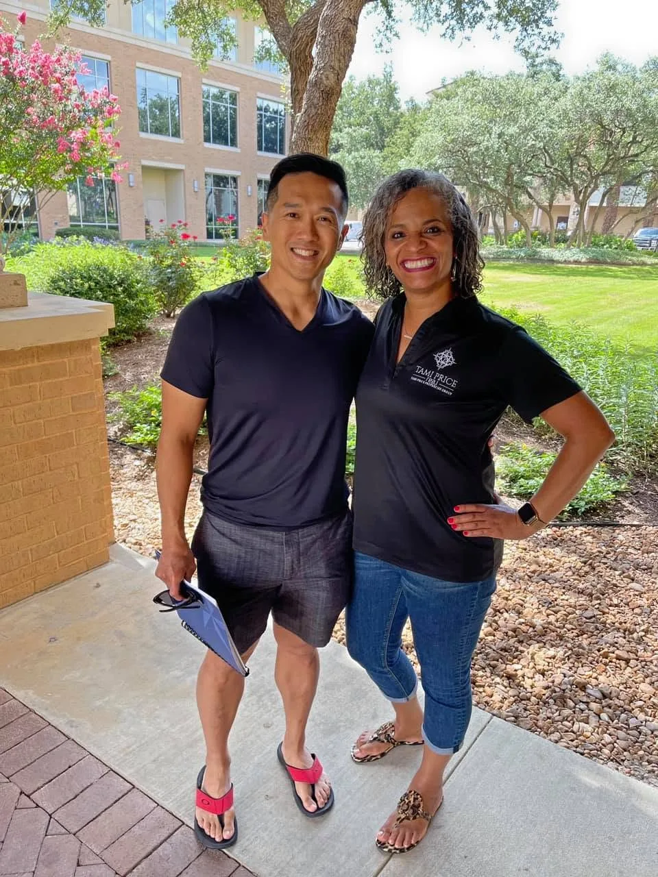 Tami Price outdoors with a colleague in a branded polo shirt in front of an office building