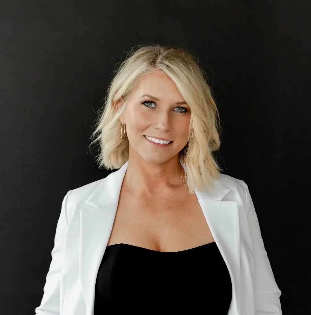 Professional headshot of Nicole Elizabeth Yaeger in a white blazer, smiling