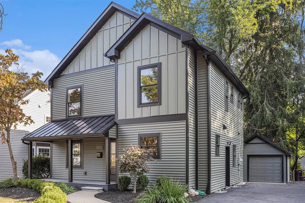 A modern two-story home with olive green siding and a black metal roof, ready for its new owners