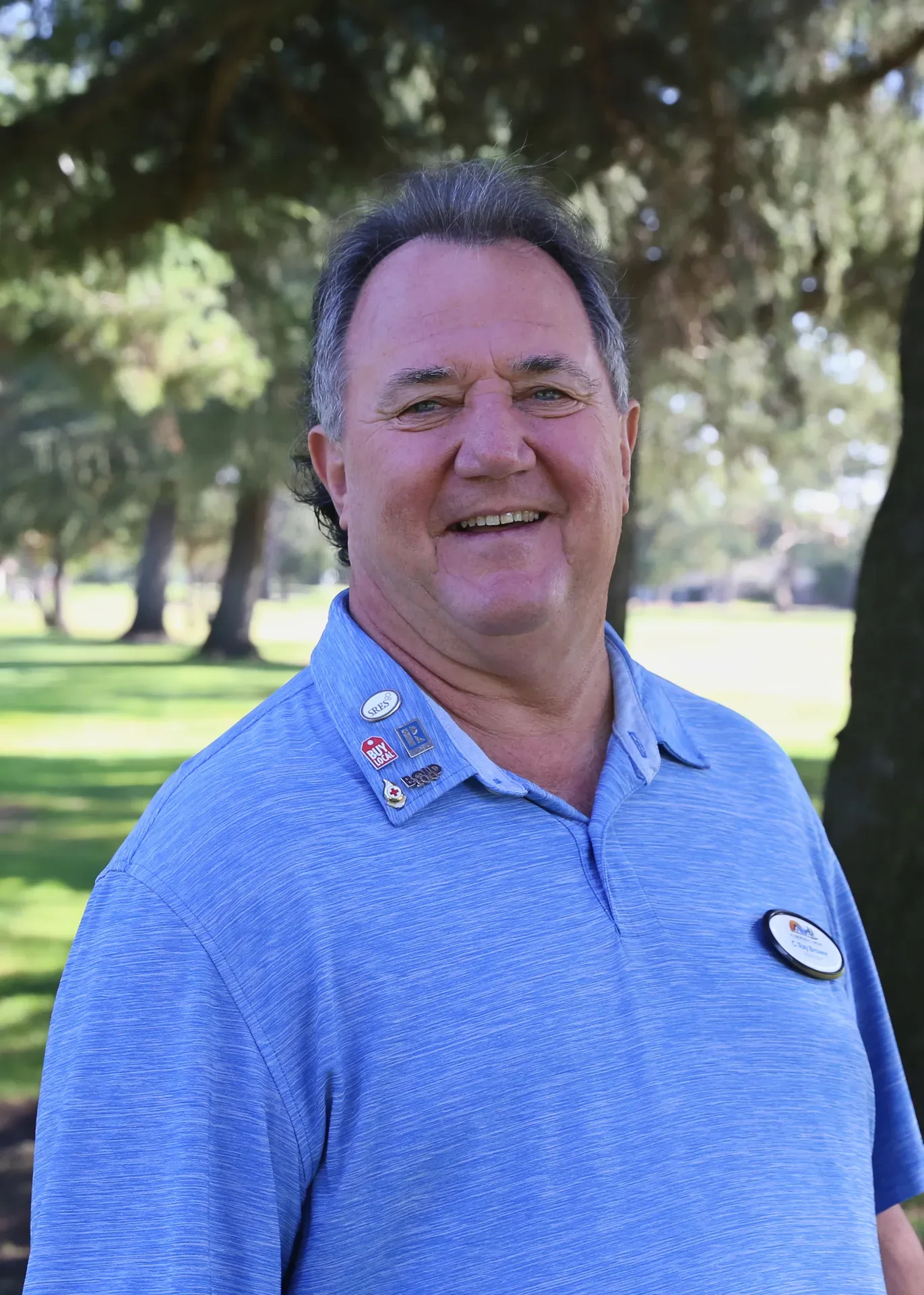C. Ray Brower smiling in a blue polo at an outdoor park