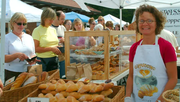 Holly Brumm Furdo at a bakery stall at the outdoor market, chatting with customers