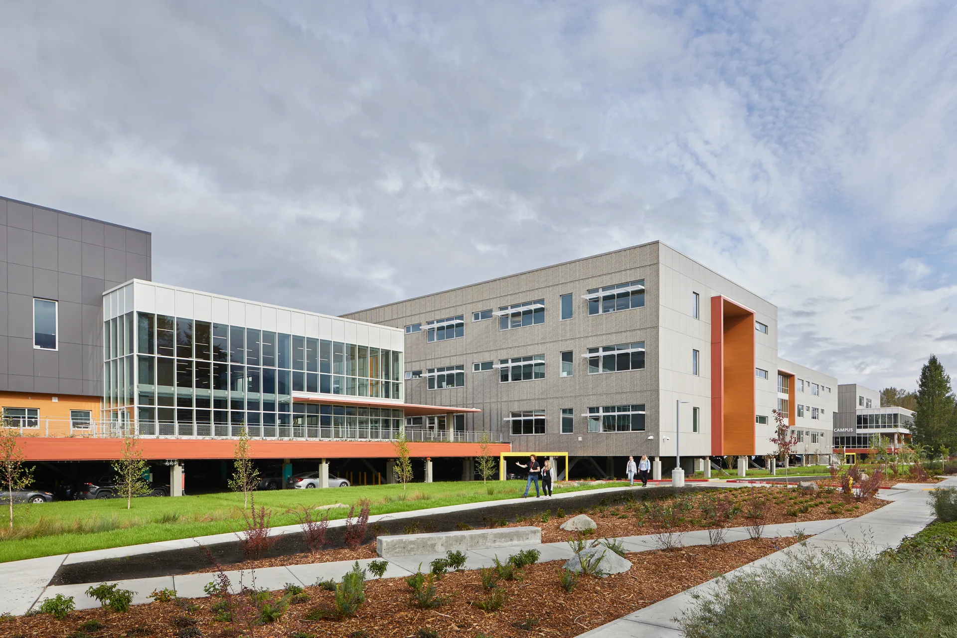 A modern Pacific Northwest school campus with evergreen foothills behind it