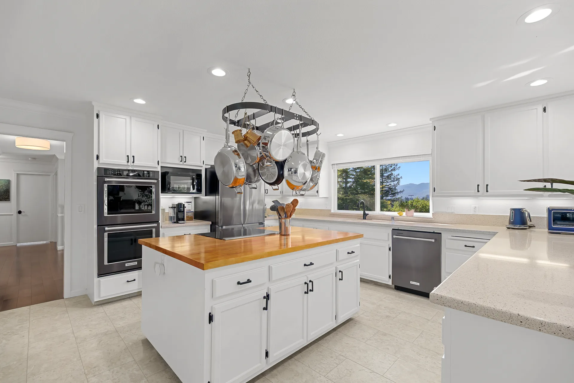Wide-angle kitchen view with shaker cabinetry, butcher-block island and tile flooring